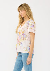[Color: Blush/Dusty Blue] A side facing image of a blonde model wearing a pink floral top with layered short sleeves and a split v-neckline. A spring feminine top for casual outings. 