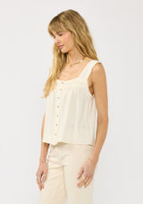 [Color: Tea] A side facing image of a blonde model wearing a bohemian off white tank top with a button front, square neckline, and wide straps with ruffle trims. 