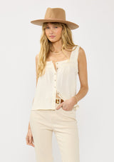 [Color: Tea] A front facing image of a blonde model wearing a bohemian off white tank top with a button front, square neckline, and wide straps with ruffle trims. 