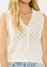 [Color: White] A detail image of a blonde model wearing a white pointelle knit vest with a v neckline and button front. 