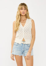 [Color: White] A front facing image of a blonde model wearing a white pointelle knit vest with a v neckline and button front. 