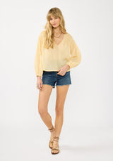 [Color: Sunshine] A front facing image of a blonde model wearing a boho yellow blouse with a v neckline, shirred shoulder detail, and long sleeves. 