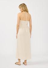 [Color: Natural] A back facing image of a blonde model wearing a beige linen blend maxi dress with a halter neck, side pockets, and a back zip up closure. 