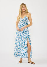 [Color: Ivory/Navy] A front facing image of a blonde model wearing a blue and white floral maxi dress with a smocked top, halter neckline, front slits, and tie back detail.