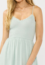 [Color: Mint] A detail image of a blonde model wearing a mint green midi dress with a smocked bust, spaghetti straps, and ruffle trim details.