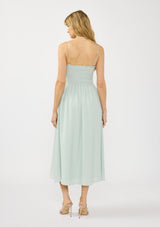 [Color: Mint] A back facing image of a blonde model wearing a mint green midi dress with a smocked bust, spaghetti straps, and ruffle trim details.