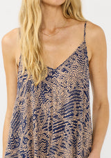 [Color: Navy/Natural] A detail image of a blonde model wearing a flowy bohemian floral print maxi dress with adjustable spaghetti straps, a v neckline, and side pockets.