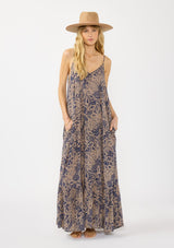 [Color: Navy/Natural] A front facing image of a blonde model wearing a flowy bohemian floral print maxi dress with adjustable spaghetti straps, a v neckline, and side pockets.