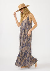 [Color: Navy/Natural] A side facing image of a blonde model wearing a flowy bohemian floral print maxi dress with adjustable spaghetti straps, a v neckline, and side pockets.
