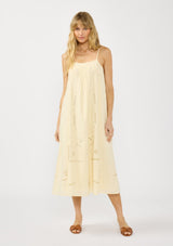 [Color: Cream] A front facing image of a blonde model wearing a flowy cutout embroidered midi dress with spaghetti straps and a back button detail. 