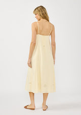 [Color: Cream] A back facing image of a blonde model wearing a flowy cutout embroidered midi dress with spaghetti straps and a back button detail. 