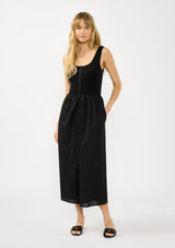 [Color: Black] A front facing image of a blonde model wearing black tank dress with a soft knit top and contrast cotton skirt. Featuring side pockets and a button front. 