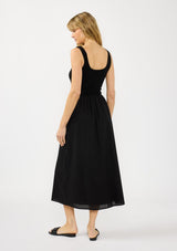 [Color: Black] A back facing image of a blonde model wearing black tank dress with a soft knit top and contrast cotton skirt. Featuring side pockets and a button front. 
