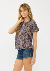 [Color: Navy/Natural] A side facing image of a blonde model wearing a navy and natural floral print top with short ruffled sleeves, a button front, and a shirred yoke. 