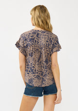 [Color: Navy/Natural] A back facing image of a blonde model wearing a navy and natural floral print top with short ruffled sleeves, a button front, and a shirred yoke. 