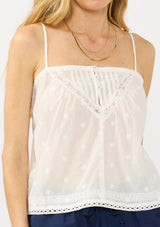 [Color: White] A detail image of a blonde model wearing a white lace camisole with a square neckline, embroidered details, and adjustable spaghetti straps. 