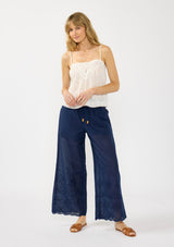 [Color: White] A front facing image of a blonde model wearing a white lace camisole with a square neckline, embroidered details, and adjustable spaghetti straps. 