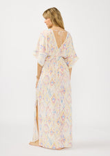 [Color: Almond/Rose] A back facing image of a blonde model wearing a pink and yellow boho print maxi dress with kimono sleeves, a smocked waist, a tie back detail, and side slits. The perfect vacation dress. 