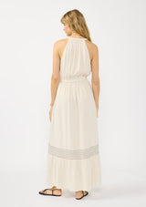 [Color: Natural] A back facing image of a blonde model wearing a beige bohemian sleeveless maxi dress with a button front top, waist belt, side pockets, and contrast stitching. 