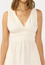 [Color: Natural/Coral] A detail image of a brunette model wearing a sleeveless maxi dress with an elastic waistline. 