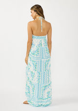 [Color: Natural/Mint] A back facing image of a brunette model wearing a mint green floral maxi dress with a halter neckline, tiered silhouette, high low hemline, ruffle trims, and side pockets. 