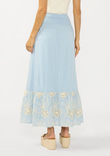 [Color: Chambray Blue/Natural] A back facing image of a light blue maxi skirt with a smocked waist and embroidered hem. 
