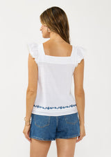 [Color: White/Blue] A back facing image of a brunette model wearing a white flutter sleeve top with blue floral embroidery, a button front, and pintucks. 