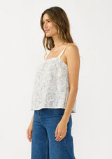 [Color: Natural/Blue] A side facing image of a brunette model wearing a blue and white bohemian tank top with a square neckline and adjustable straps with lace trim.