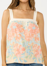 [Color: Natural/Coral] A detail image of a brunette model wearing a coral floral tank top with solid back and a square neckline. 