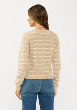 [Color: Heather Sand/White] A back facing image of a brunette model wearing a light brown pointelle sweater with a v-neckline, button front, and a scalloped trim. 