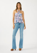 [Color: Natural/Dusty Rose] A front facing image of brunette model wearing a tropical pink and blue halter top with a gathered bust and smocked back. Styled with light wash denim and brown block heels. 
