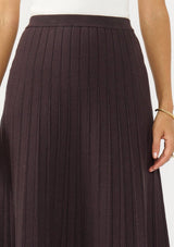 [Color: Chocolate] A detail image of a brunette model wearing a brown ribbed knit maxi skirt with an elastic waistband. 
