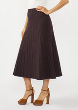 [Color: Chocolate] A side facing image of a brunette model wearing a brown ribbed knit maxi skirt with an elastic waistband. 