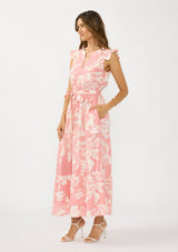 [Color: Salmon/Ivory] A side facing image of a brunette model wearing a coral floral print maxi dress with a flutter cap sleeves, a split v neckline, a tiered skirt, and a waist belt. 