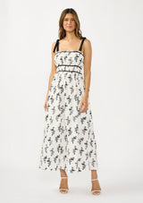 [Color: White/Black] A front facing image of a brunette model wearing a white and black floral eyelet midi dress with tie shoulders, a square neckline, and a gathered bodice.
