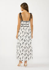 [Color: White/Black] A back facing image of a brunette model wearing a white and black floral eyelet midi dress with tie shoulders, a square neckline, and a gathered bodice.