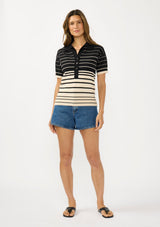 [Color: Black/Buttercream] A front facing image of a brunette model wearing a black and beige collared sweater top with a striped design, a button front, and short sleeves. 