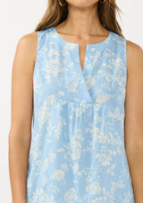 [Color: Blue/Ivory] A detail image of a brunette model wearing a blue floral sleeveless mini dress with a split v neckline and side pockets.  