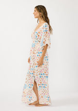 [Color: Ivory/Orange] A side facing image of a brunette model wearing a blue and orange kimono sleeve maxi dress with a deep v neckline, smocked waist, tie back detail, and side slits. 