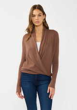 [Color: Clove] A front facing image of a Lovestitch model wearing a chic brown waffle knit wrap front sweater with long sleeves, a v neckline, and a button closure at the back. The long ties can be styled in multiple ways.