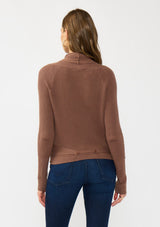 [Color: Clove] A back facing image of a Lovestitch model wearing a chic brown waffle knit wrap front sweater with long sleeves, a v neckline, and a button closure at the back. The long ties can be styled in multiple ways.