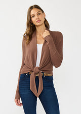[Color: Clove] A photo of a Lovestitch model wearing a chic brown waffle knit wrap front sweater with long sleeves, a v neckline, and a button closure at the back. The long ties can be styled in multiple ways.