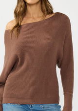 [Color: Clove] A detail image of a brunette model wearing a brown waffle knit pullover sweater. With long sleeves, a relaxed fit, and a wide neckline that can be worn off the shoulder.