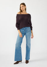 [Color: Aubergine] A front facing image of a brunette model wearing a dark purple waffle knit pullover sweater. With long sleeves, a relaxed fit, and a wide neckline that can be worn off the shoulder.