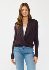 [Color: Aubergine] A front facing image of a Lovestitch model wearing a chic dark purple waffle knit wrap front sweater with long sleeves, a v neckline, and a button closure at the back. The long ties can be styled in multiple ways.