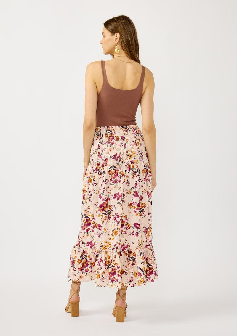 [Color: Almond/Wine] A back facing image of a blonde model wearing a convertible pink floral print skirt with a smocked waist and a ruffle trimmed hem. 