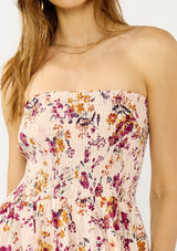 [Color: Almond/Wine] A detail image of a blonde model wearing a convertible pink floral print midi dress with a smocked bodice and a ruffle trimmed hem. 