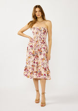 [Color: Almond/Wine] A front facing image of a blonde model wearing a convertible pink floral print midi dress with a smocked bodice and a ruffle trimmed hem. 