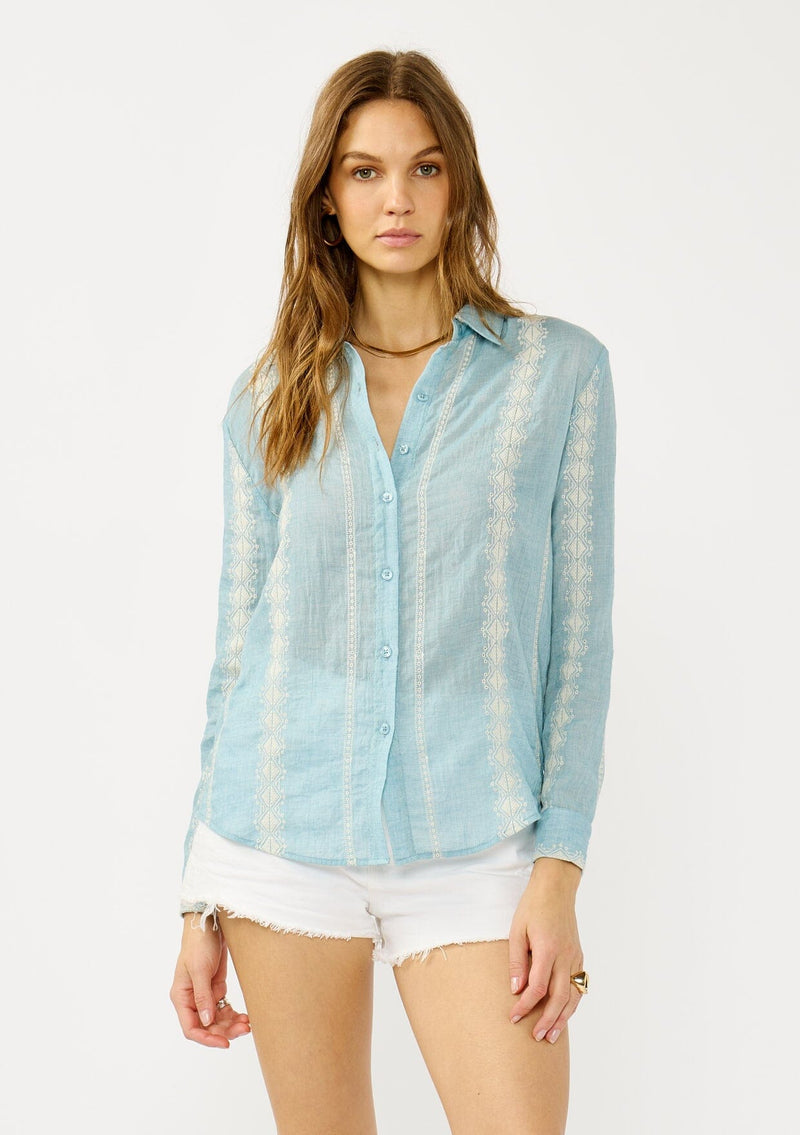 [Color: Light Blue/Ivory] A front facing image of a blonde model wearing a light blue shirt with an embroidered stripe pattern,  a classic collar neckline, and button front. A boho inspired shirt for festivals, casual outings, and country events. 