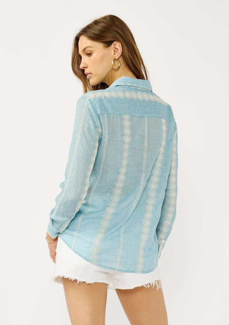 [Color: Light Blue/Ivory] A back facing image of a blonde model wearing a light blue shirt with an embroidered stripe pattern,  a classic collar neckline, and button front. A boho inspired shirt for festivals, casual outings, and country events. 